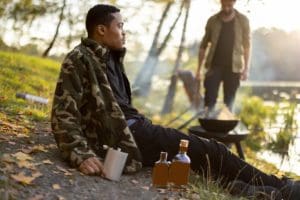 Guy with alcoholic drinks on fishing on lake